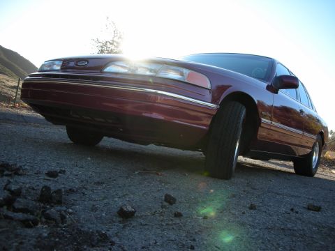 1992 Ford Crown Victoria - A maroon 1992 Ford Crown Victoria is shown from a low angle on a sunny day.
