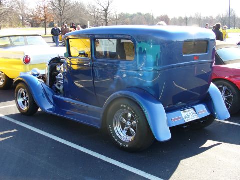 1991 Ford Probe - A custom blue sedan with a prominent engine and large rear wheels is parked at an outdoor event.
