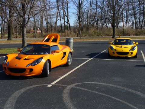 1991 Ford Probe - Two sports cars, one orange and one yellow, are parked in a lot on a sunny day.