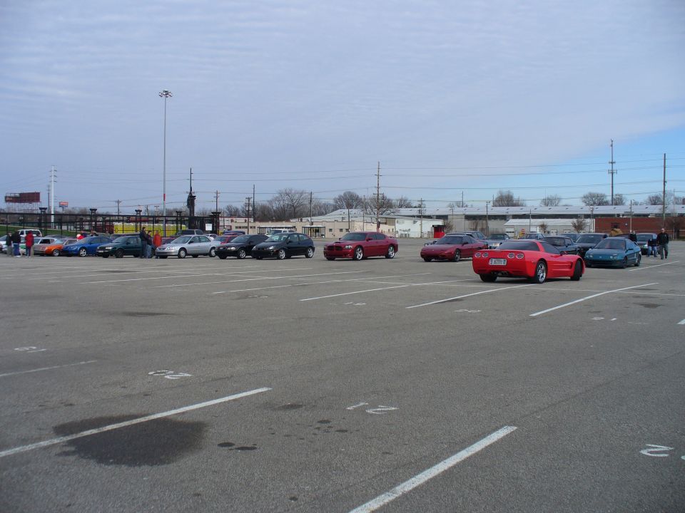 Red sports car from rear in a parking lot with other vehicles