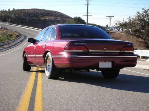 1992 Ford Crown Victoria - Rear view of a maroon 1992 Ford Crown Victoria LX on a road with double yellow lines.