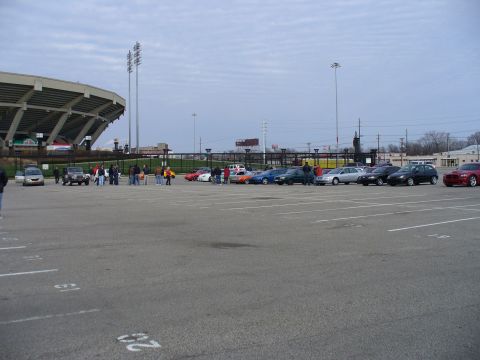1991 Ford Probe - A stadium parking lot is filled with various cars under a cloudy sky.