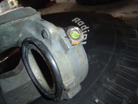 1986 Ford Bronco - A close-up view of a brake caliper part, resting on a tire tread.