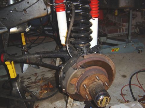 1986 Ford Bronco - Close-up of a vehicle's front suspension and brake components, including a coil spring and disc brake assembly.