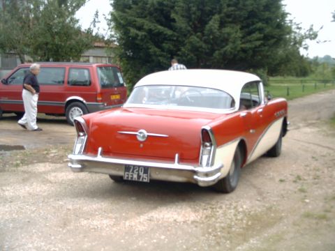 1991 Ford Crown Victoria - Rear view of a two-tone 1956 Buick Century parked next to a red van.