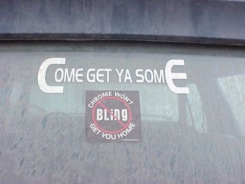 1985 Ford Bronco - A rear window displays two stickers, one with a humorous message about chrome and another with a more direct invitation.