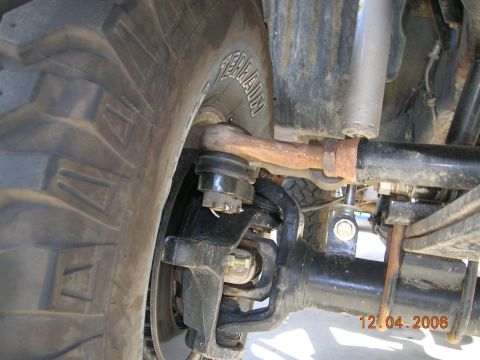 1985 Ford Bronco - Detailed view of the front axle and suspension system, showing the steering linkage and shock absorber.