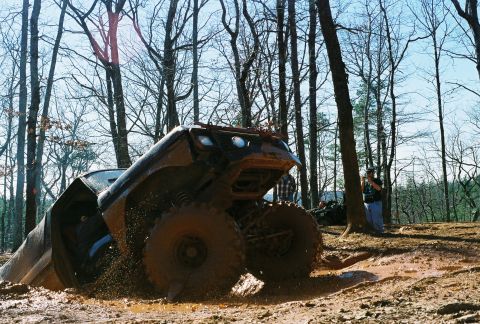 1978 Ford Bronco - This off-road vehicle is deeply stuck in the mud, with its front end angled upwards in a wooded area.