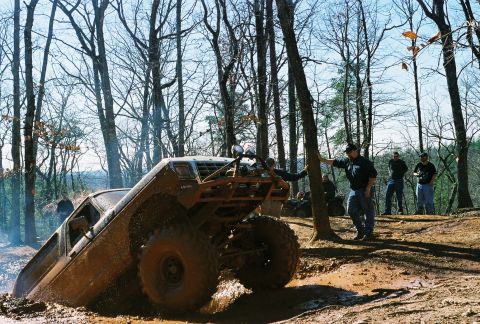 1978 Ford Bronco - A 1978 Ford Bronco navigates a muddy off-road course with spectators watching.