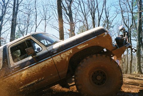 1978 Ford Bronco - Muddy 1978 Ford Bronco navigating a wooded trail.