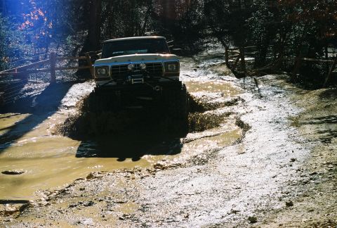 1978 Ford Bronco - This 1978 Ford Bronco navigates a challenging muddy terrain on a wooded path.