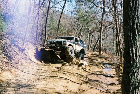 1978 Ford Bronco - A 1978 Ford Bronco navigates a challenging off-road trail with steep inclines and muddy puddles.
