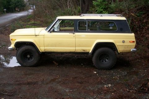 1974 Ford F-100 - This Jeep Cherokee SJ is parked off-road on a muddy track, with trees in the background.