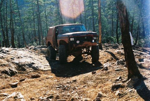 1978 Ford Bronco - A modified 1978 Ford Bronco navigates a challenging off-road course through a dense forest.