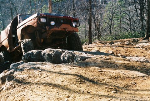 1978 Ford Bronco - This heavily modified off-road vehicle navigates a rocky trail in a wooded area.