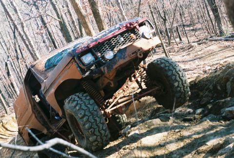 1978 Ford Bronco - This heavily modified off-road vehicle navigates a challenging, muddy, and rocky trail.