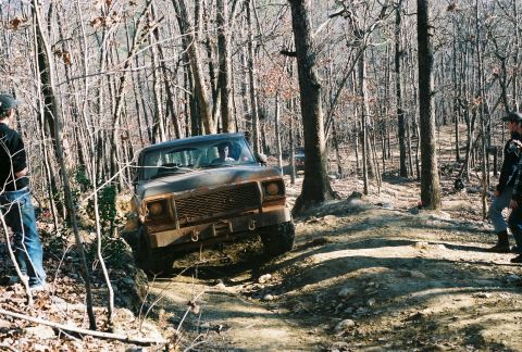 1978 Ford Bronco - A 1978 Ford Bronco navigates a challenging off-road course through a dense forest.