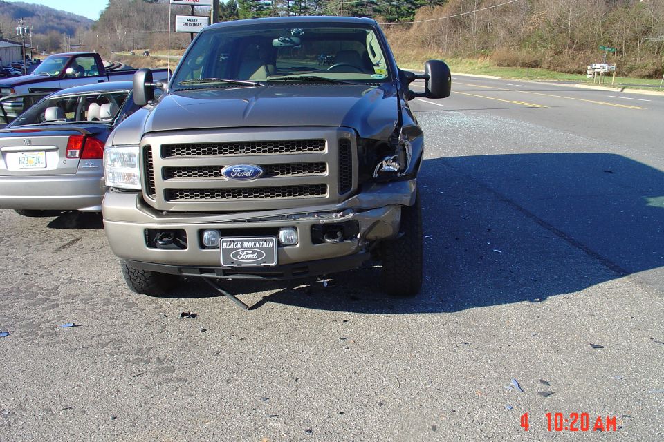 Front of tan Ford truck with crash damage to passenger-side fender and bumper