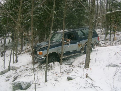 Ford Bronco stuck in snow off-road, trees around