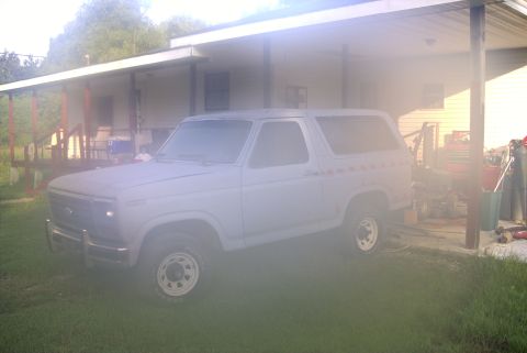 1984 Ford Bronco - This Ford Bronco is parked on a grassy lawn in front of a building with a long, covered porch.