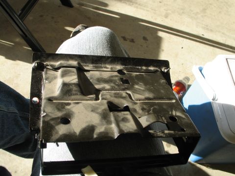 1995 Ford Bronco - A metal bracket, possibly a switch mount, is held by a person wearing jeans.