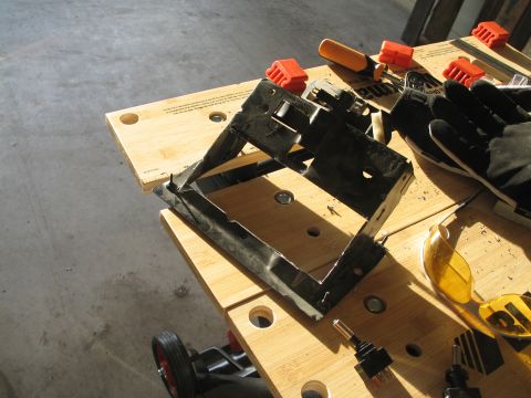 1995 Ford Bronco - A black plastic bracket sits on a wooden workbench, surrounded by tools and work gloves.