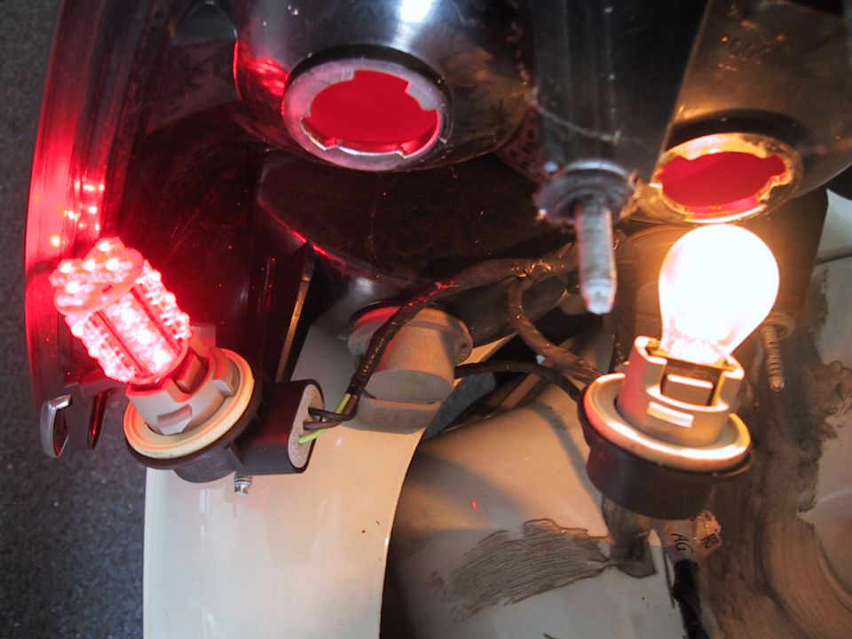 Car tail light assembly with one LED bulb lit red and one incandescent bulb lit yellow