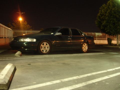 1993 Ford Taurus - Dark 1993 Ford Taurus sedan parked in a lot at night, showing its side profile.