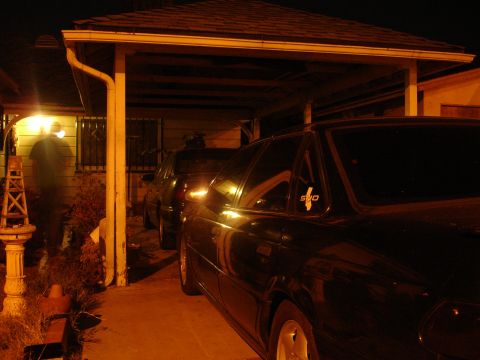 1993 Ford Taurus - A black sedan with a 'SHO' decal is parked under a carport at night, with another vehicle behind it.
