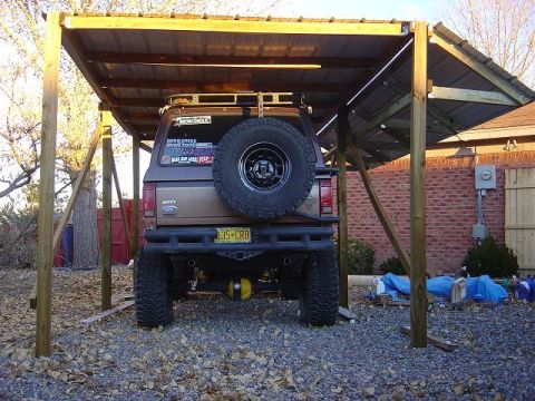 1986 Ford Bronco II - This 1986 Ford Bronco II is parked under a makeshift shelter, a spare tire on the rear and a custom bumper.