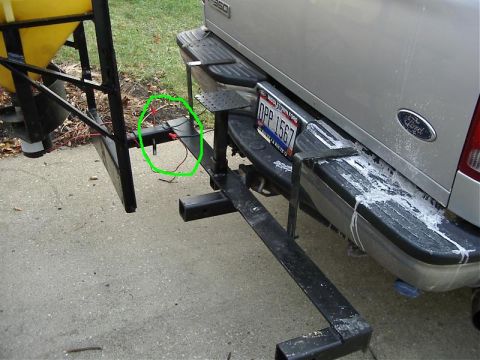 1985 Ford F-150 - The rear of a Ford pickup truck is shown with a trailer hitch and a yellow spreader attachment, with some wiring visible.