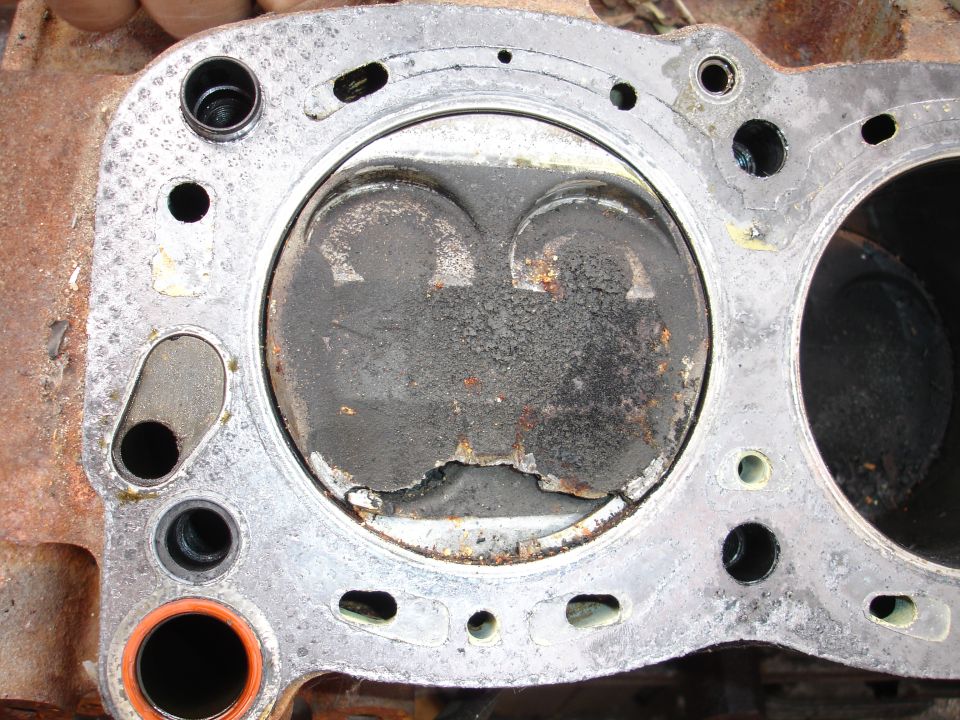 Cylinder head deck with head gasket, carbon-caked combustion chamber and rust staining