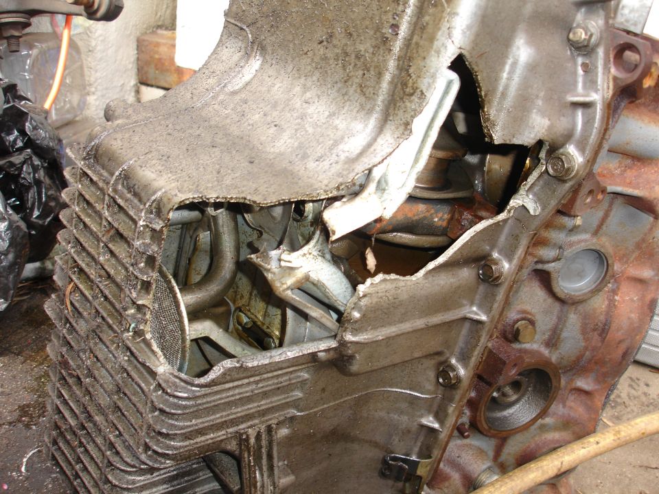 Engine block with a large hole torn through the steel oil pan exposing the crank