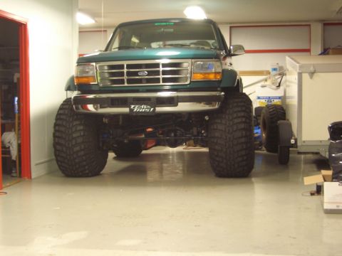 1996 Ford Bronco - This modified Ford Bronco is parked indoors, its massive tires and lifted suspension.