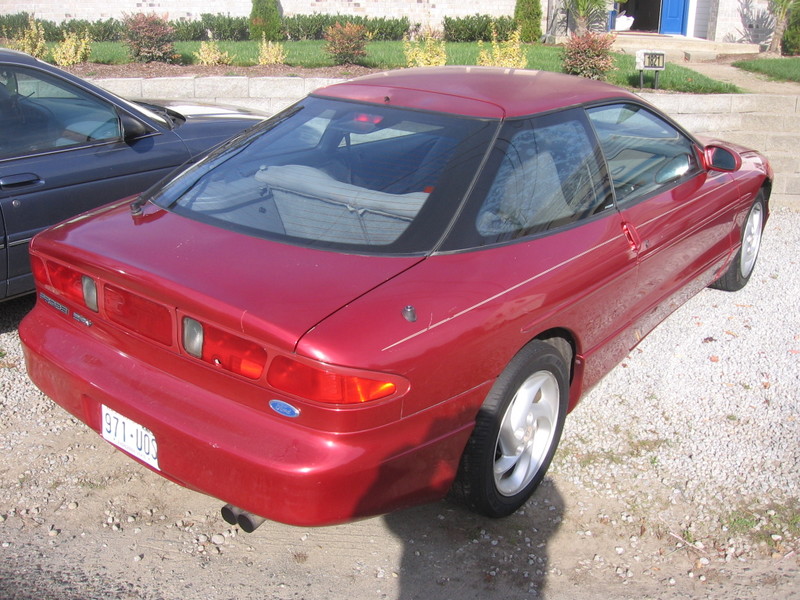 Red 1995 Ford Probe parked next to a dark blue car, rear 3/4 view