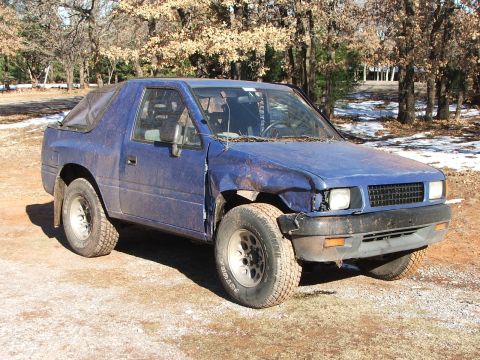 1990 Dodge Shadow - This blue SUV, likely an Isuzu Rodeo, has a soft top and visible damage to its front end.