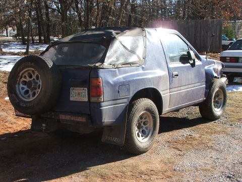 1990 Dodge Shadow - This Isuzu Amigo has a soft top and a spare tire mounted on the rear, with visible damage to the front fender.