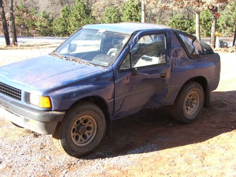1990 Dodge Shadow - A blue pickup truck sits on a gravel surface with trees in the background.