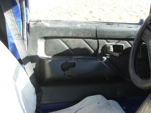 1990 Dodge Shadow - The interior door panel shows significant wear and tear, including a large rip in the plastic trim.