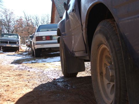 1990 Dodge Shadow - A dark pickup truck is seen from the rear, parked outdoors with other vehicles visible.