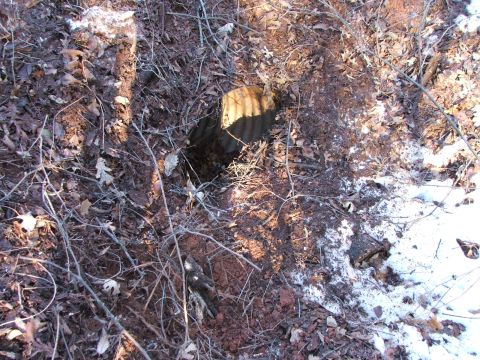 1990 Dodge Shadow - A corrugated pipe is partially buried in the ground, with fallen leaves and patches of snow visible around it.