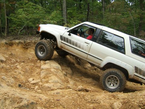 1993 Ford Bronco - Modified 1984 Toyota 4Runner tackling challenging off-road obstacles on a dirt trail.