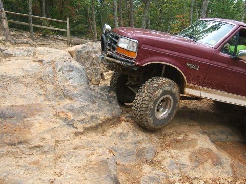 1993 Ford Bronco - 1993 Ford Bronco tackling a challenging off-road course with large rocks.
