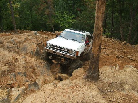 1993 Ford Bronco - White Toyota 4Runner tackling a challenging off-road course with large rocks.