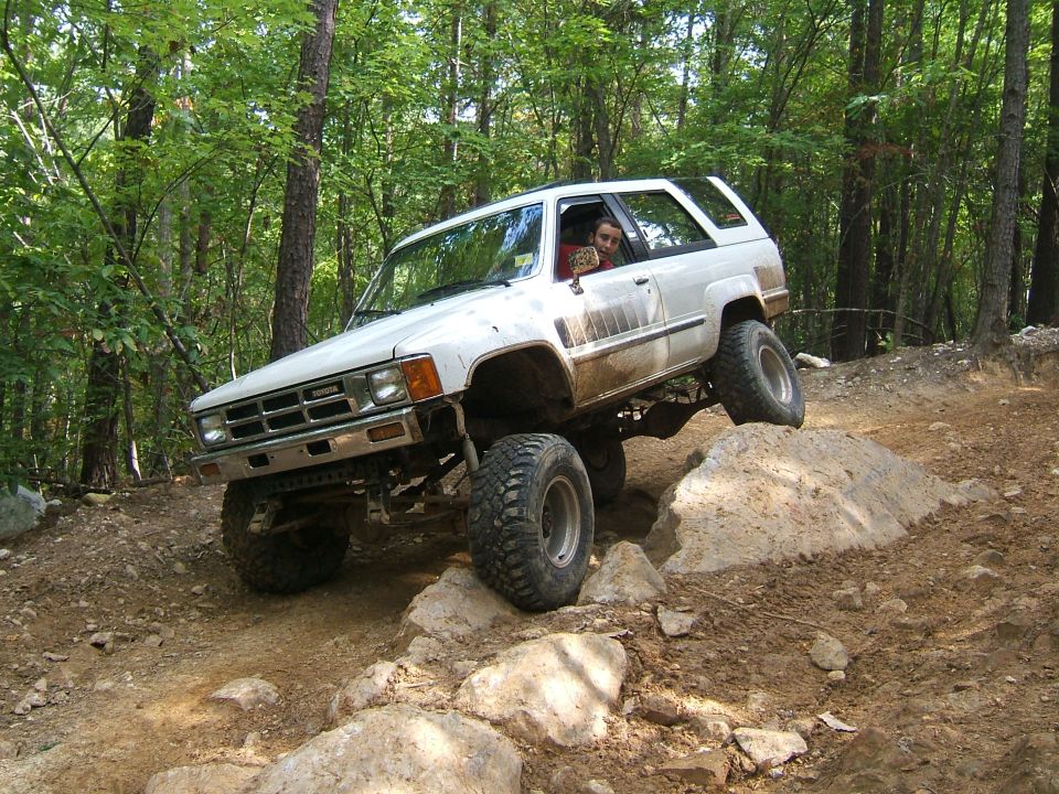 White Toyota 4Runner off-roading over rocks on a dirt trail