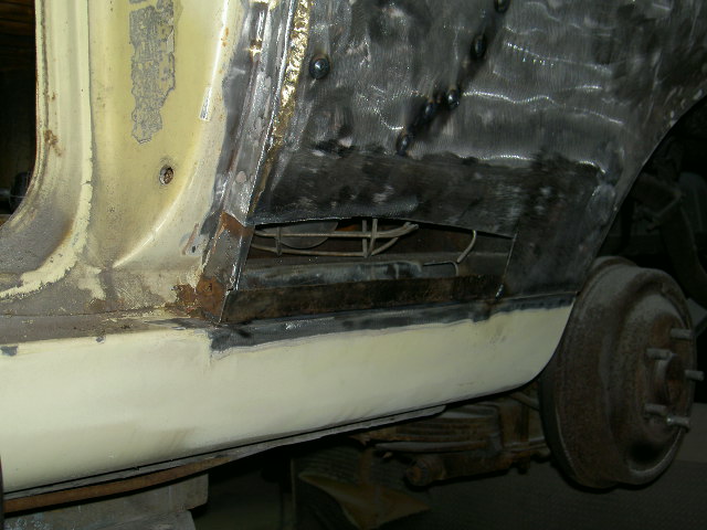 Side panel of a vehicle with rust repair and welding visible