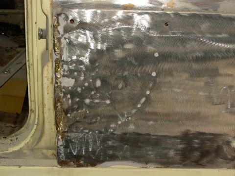 1967 Ford Ranchero - Close-up of a car door undergoing repair with a new metal patch.