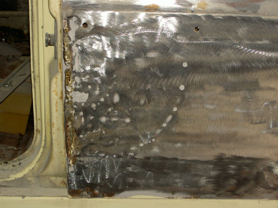 Metal patch on a car door, showing grinding marks and some rust