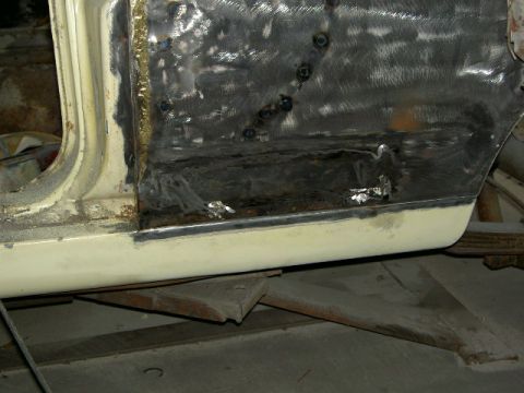 1967 Ford Ranchero - The lower body panel of a vehicle is undergoing repair work, showing welded metal and primer.