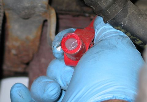 1994 Ford Bronco - A person in blue gloves uses a red socket to remove a spark plug.